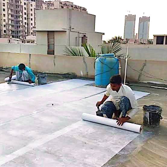 Workers preparing and applying roof waterproofing sheets