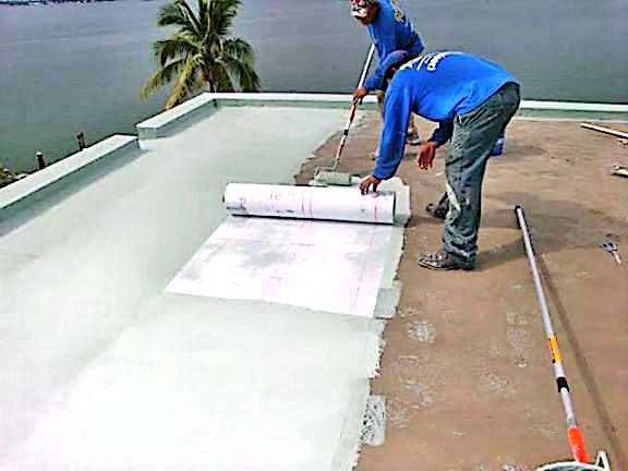 Worker installing a waterproofing membrane with a roller